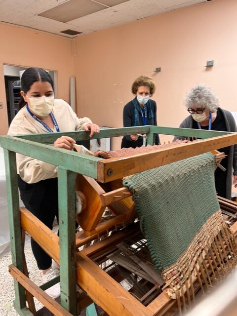 Rancho OTs delicately dusting and restoring a large loom